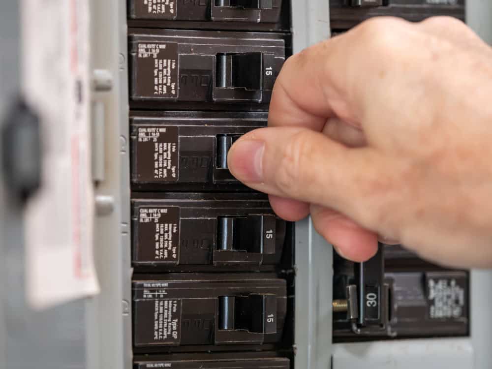 Person's hand switching off electrical breaker